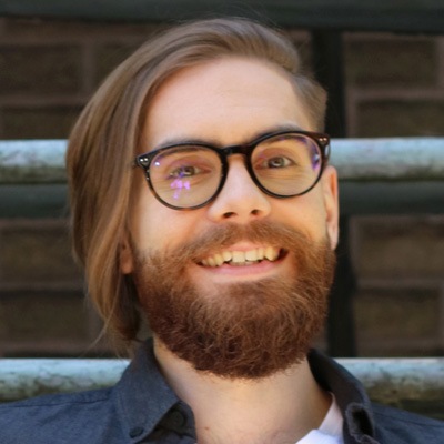 A beaming man with a well-groomed beard and glasses, exuding a cheerful and approachable vibe.