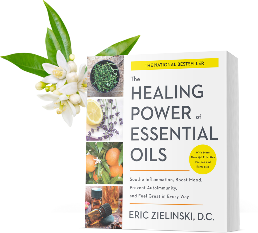 A vivid display of a book titled "the healing power of essential oils" by eric zielinski, d.c., surrounded by fresh plants and citrus fruits suggesting natural remedies and aromatherapy for wellbeing.