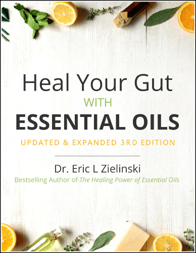A book cover titled "heal your gut with essential oils" by dr. eric z, expanded 3rd edition, from the bestselling author of "the healing power of essential oils", featuring a backdrop of fresh lemon slices and green leaves with a rustic wooden texture.