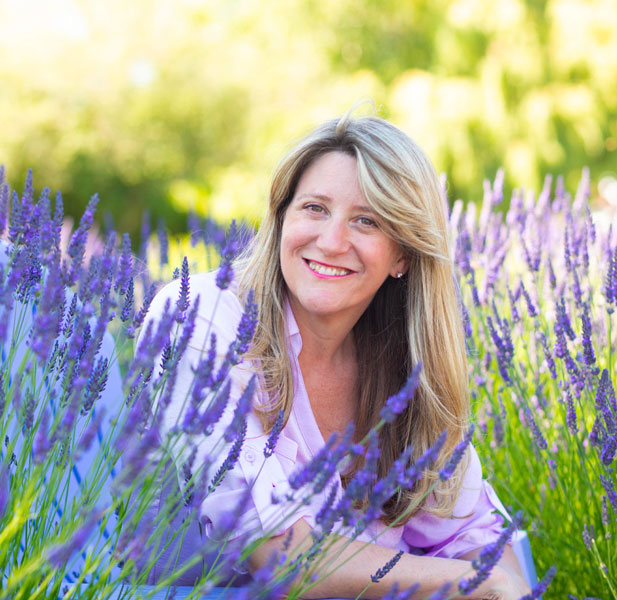 A smiling woman enjoying a serene moment in a field of lavender.